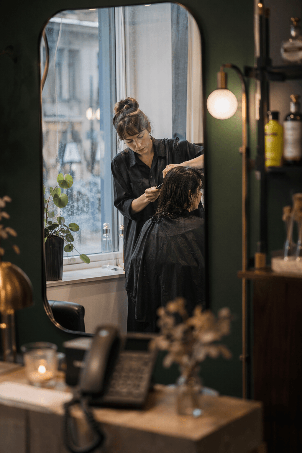 Stylist mid-cut while the reception phone goes unanswered — Skaala takes the booking in the meantime