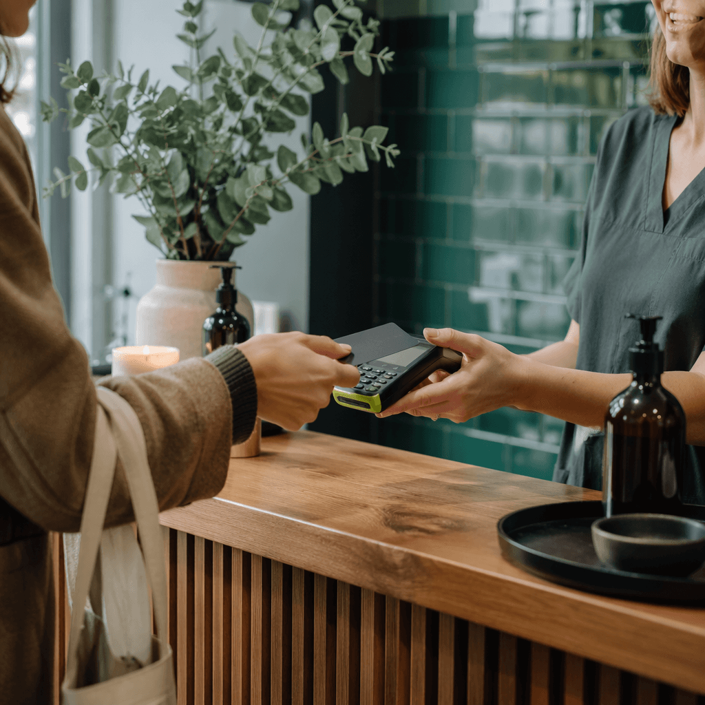 Customer tapping a card to pay at a calm massage-studio counter